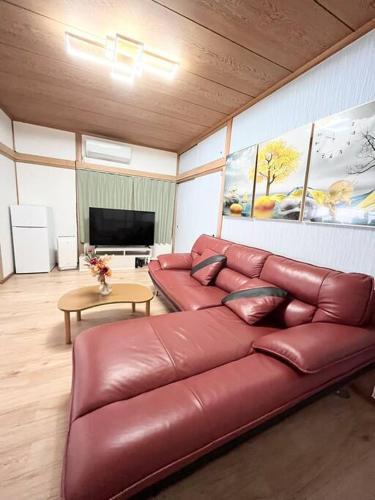 a leather couch in a living room with a television at 源泉かけ流し温泉付き貸し切り別荘白浜観光に最適の立地14名宿泊可能 in Shirahama
