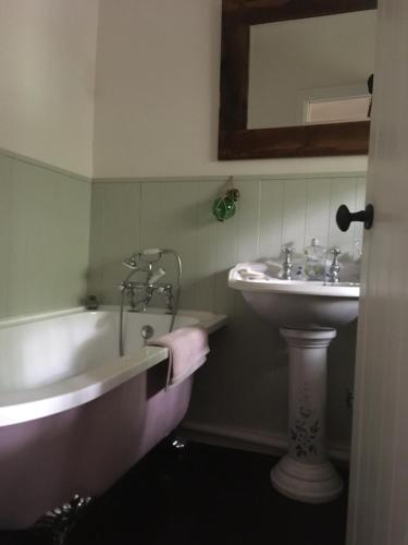 a bathroom with a sink and a bath tub next to a sink at Mermaid Cottage in West Lulworth