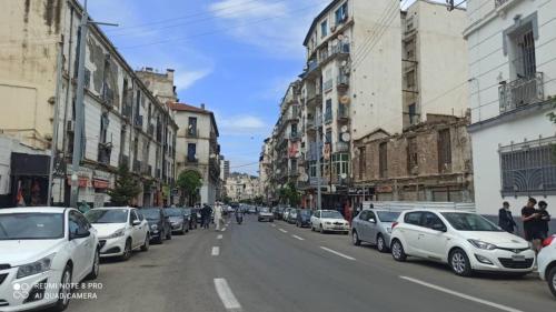 une rue avec des voitures garées sur le côté de la route dans l'établissement Farah, à El Madania