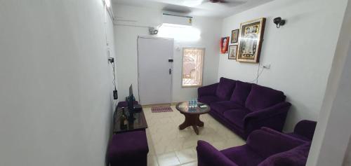 una sala de estar con sofás morados y una mesa. en Halls Tower, en Chennai