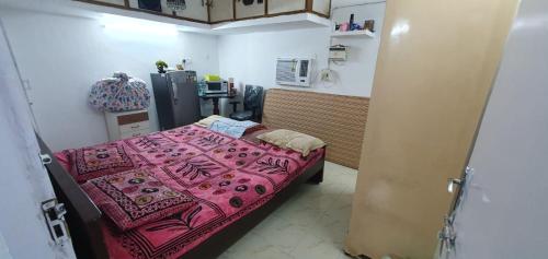 a small room with a bed with a pink blanket at Halls Tower in Chennai