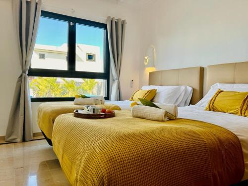 een slaapkamer met 2 bedden met gele lakens en een raam bij Villa Sunset Zafiro in Playa Blanca