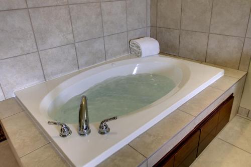 a bath tub in a bathroom with a sink at Cobblestone Inn & Suites - Hartington in Hartington