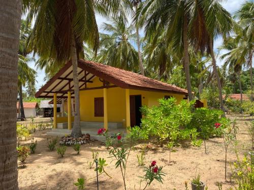 a small yellow house with palm trees at Kitelantis Hotel and Resort in Kalpitiya