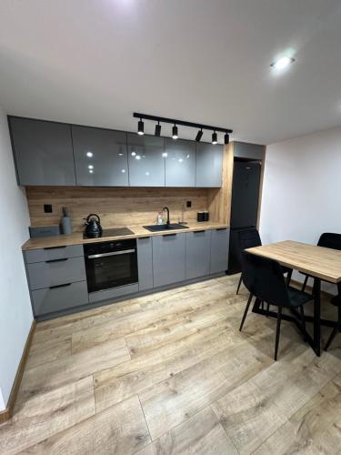 cocina con suelo de madera y mesa con sillas en LUX HOUSE Roztocze, en Krasnobród