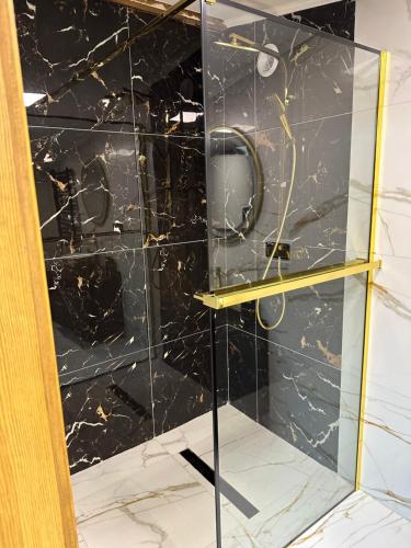 a glass shower with a black marble wall at LUX HOUSE Roztocze Sauna i Bania z hydromasażem in Krasnobród