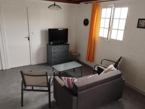 un salon avec un canapé, des chaises et une télévision dans l'établissement la maisonnette à 1200 m de la mer, à Agon-Coutainville