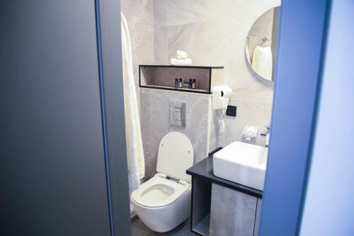 La salle de bains est pourvue de toilettes blanches et d'un lavabo. dans l'établissement Riverside Burabay Hotel, à Borovoe