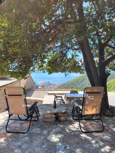 twee stoelen en een picknicktafel onder een boom bij Authentic Mediterranean House with Postcard Sea View in Tivat