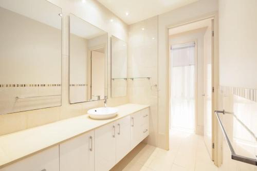 a white bathroom with a sink and a mirror at 3BR Serene Waterfront Retreat with pool & dock in Gold Coast