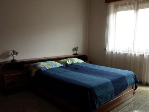 1 dormitorio con 1 cama con edredón azul y ventana en Ferienwohnung für 6 Personen ca 120 qm in Capo d'Orlando, Sizilien Nordküste von Sizilien, en Capo dʼOrlando
