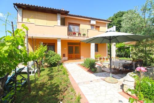 a house with an umbrella and a patio at Ferienwohnung für 6 Personen ca 90 qm in Muntic, Istrien Südküste von Istrien in Muntić