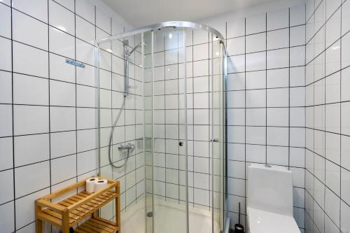 a white tiled bathroom with a shower and a toilet at Stylish newly renovated 1 BR Apt on the modern Abashidze street in Tbilisi City