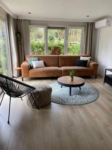 a living room with a couch and a table at Sfeervol chalet Hoenderloo, de Veluwe in Hoenderloo