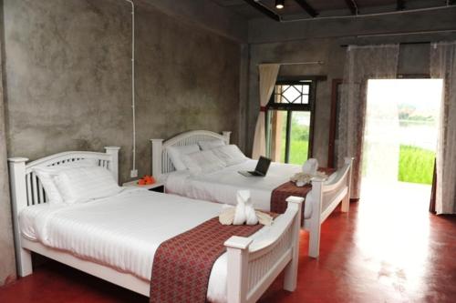 a bedroom with two beds and a laptop on top of them at Phu-Anna Eco House in Hot