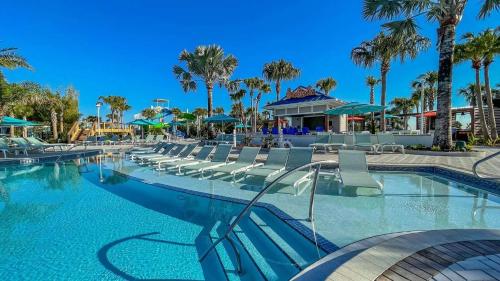 a pool at a resort with chairs and palm trees at Enchanted Villa in Orlando