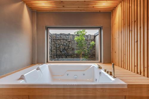 a bath tub in a room with a window at Le Village Aewol G in Jeju