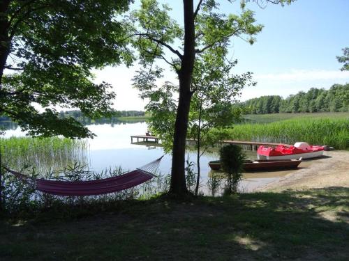 a hammock on the shore of a lake with two boats at Dereniowe Wzgórze in Sejny