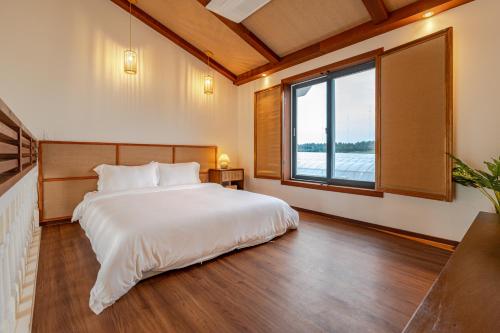 a bedroom with a large bed and a large window at Le Village Aewol G in Jeju