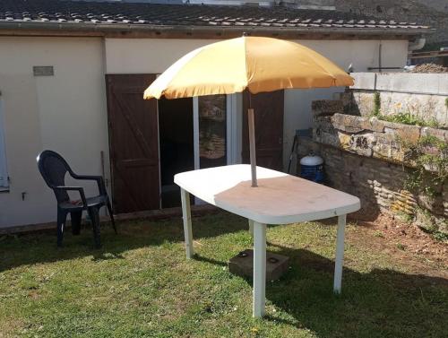 einen Tisch mit gelbem Regenschirm auf dem Gras in der Unterkunft Maison avec jardin in Caen