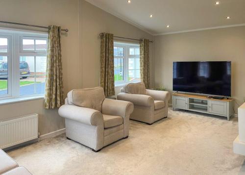 a living room with two chairs and a flat screen tv at Arran Hills in Kilwinning