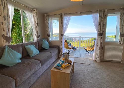 a living room with a couch and a view of the ocean at Lynmouth Holiday Retreat in Lynton