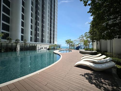 a swimming pool with lounge chairs next to a building at SummerDay Seaview Studio Apartment at Kota Kinabalu City Centre in Kota Kinabalu