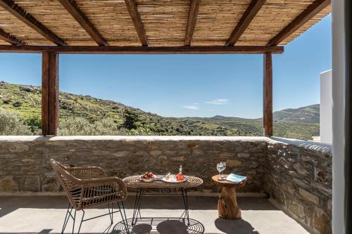a patio with a table and chairs on a stone wall at Ktima Drilli - Experience the authentic Naxian lifestyle in Áno Potamiá