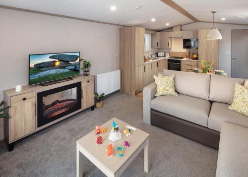 a living room with a couch and a tv and a table at Heads Of Ayr Holiday Park in Ayr