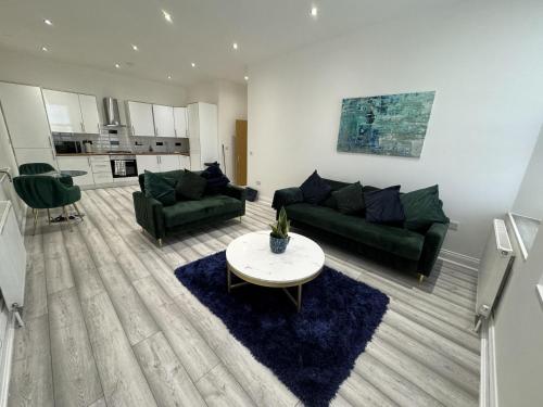 una sala de estar con 2 sofás verdes y una mesa. en Gorgeous Spacious Apartment with Sea View, en Walton-on-the-Naze