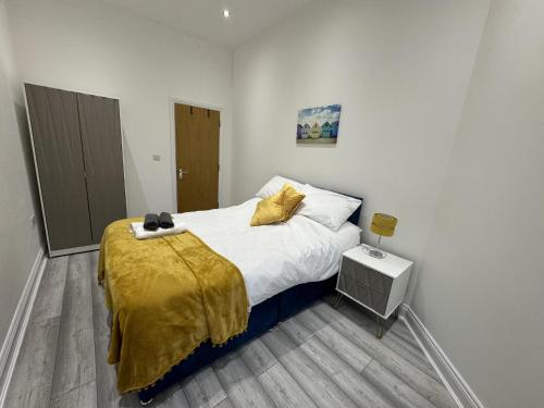 a bedroom with a bed with a yellow blanket on it at Gorgeous Spacious Apartment with Sea View in Walton-on-the-Naze