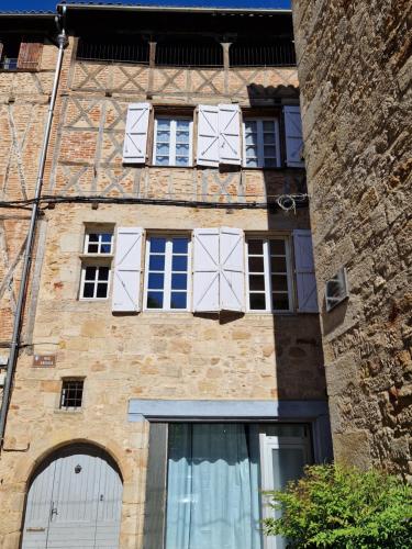 un edificio de ladrillo con puertas y ventanas blancas en Maison Ambre, en Figeac