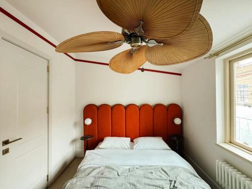 a bedroom with a red headboard and a ceiling fan at Chic Studio near Fabrika-By Wehost in Tbilisi City
