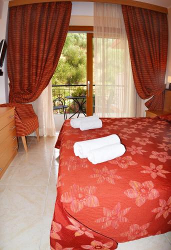 a bedroom with a red bed with towels on it at Petros Italos in Neos Marmaras