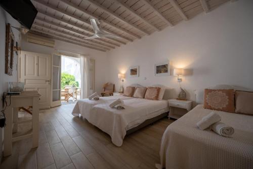 a white bedroom with two beds and a window at TWINS-TRISA APARTMENTS in Ornos
