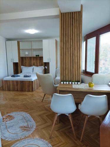 a bedroom with a bed and two white chairs at Apartman Rajska Banja in Vrnjačka Banja
