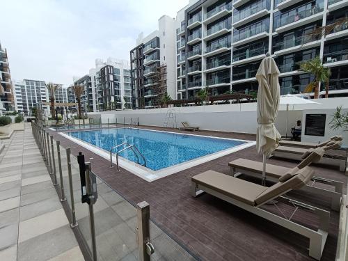 a swimming pool with two lounge chairs and an umbrella at Luxury Staycation Studio in Royal Neighbourhood in Dubai