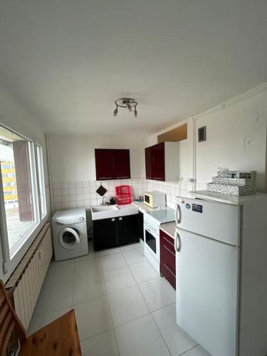 een keuken met witte apparaten en rode kasten bij Spacieux appartement avec balcon in Belfort