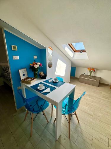 a dining room with a white table and blue chairs at Sky Loft in Alba