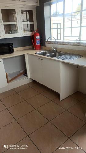 a kitchen with white cabinets and a sink at JOLLY'S PARK GUEST HOUSE in Roodepoort