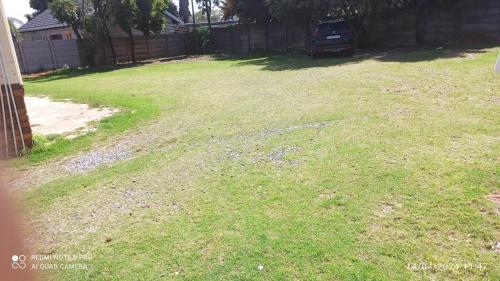 a yard with grass and gravel and a fence at JOLLY'S PARK GUEST HOUSE in Roodepoort