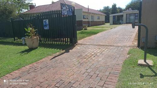 a brick driveway in front of a fence at JOLLY'S PARK GUEST HOUSE in Roodepoort