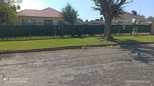 a house with a fence and a tree in a yard at JOLLY'S PARK GUEST HOUSE in Roodepoort