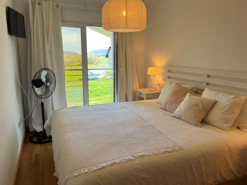 1 dormitorio con 1 cama con ventilador y ventana en Apartamento Suite mirando al mar, en Porto de Espasante
