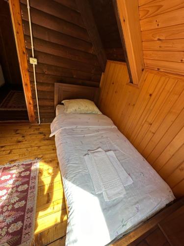 Cama pequeña en habitación de madera con colchón en Guest House Rilindja Valbone en Valbonë