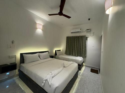 een slaapkamer met 2 bedden en een plafondventilator bij Le Tamara Luxury in Auroville