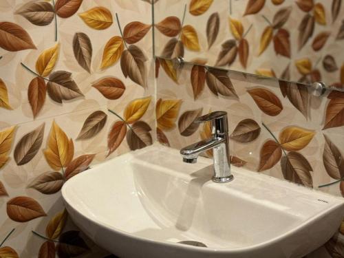 a bathroom sink with a leaf pattern on the wall at Le Tamara Luxury in Auroville