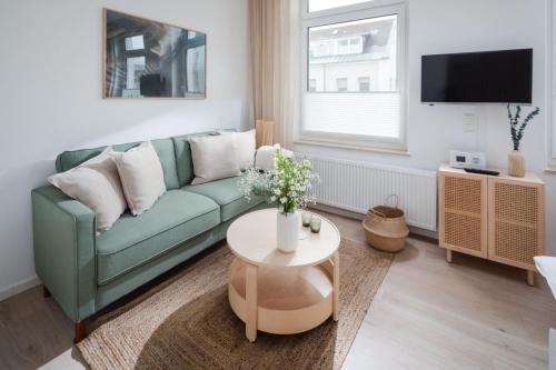 a living room with a green couch and a table at Bismarck 1884 B6 in Norderney