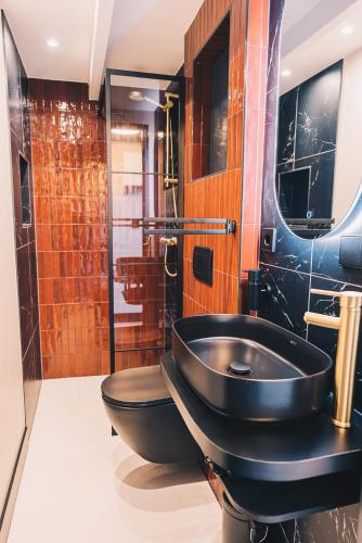 a bathroom with a black toilet and a sink at LVM Stays in The Hague