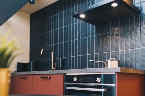 een keuken met een zwart betegelde muur bij LVM Stays in Den Haag